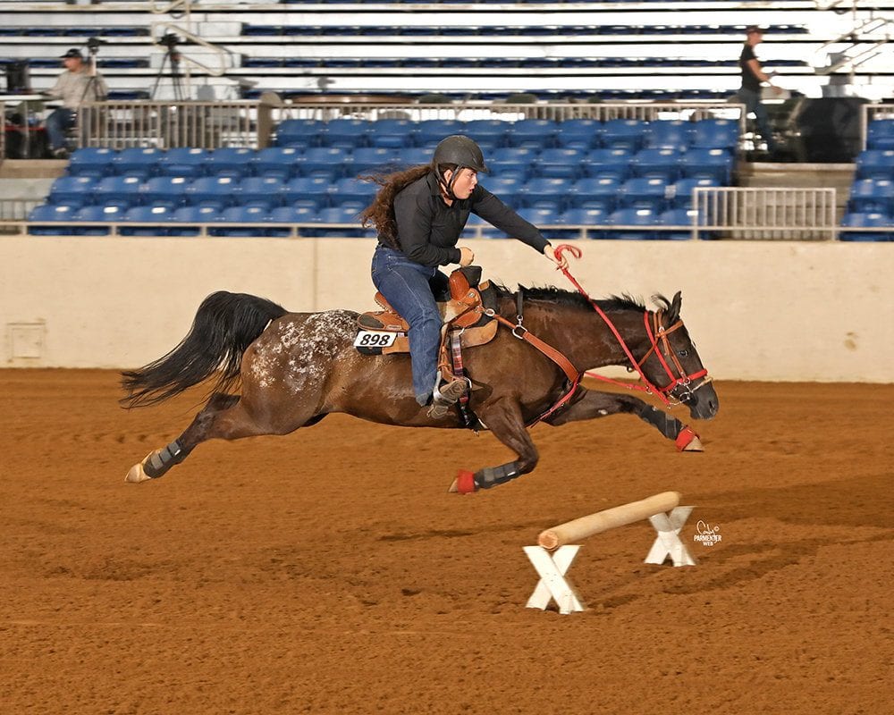 A rider turns a barrel in an indoor arena.